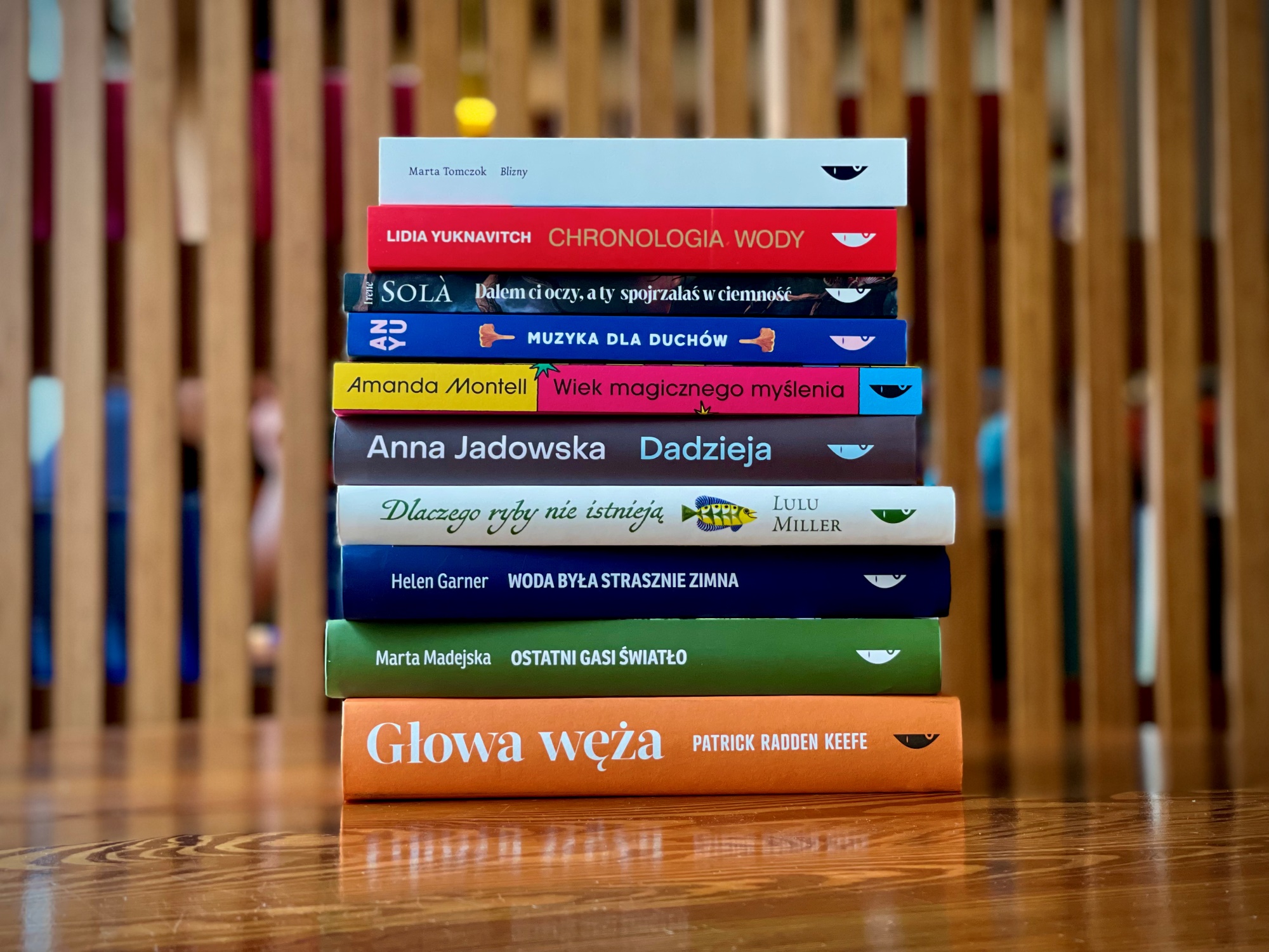 Stos książek wydawnictwa Czarne ułożonych jedna na drugiej; widoczne grzbiety z tytułami i nazwiskami autorów i autorek.