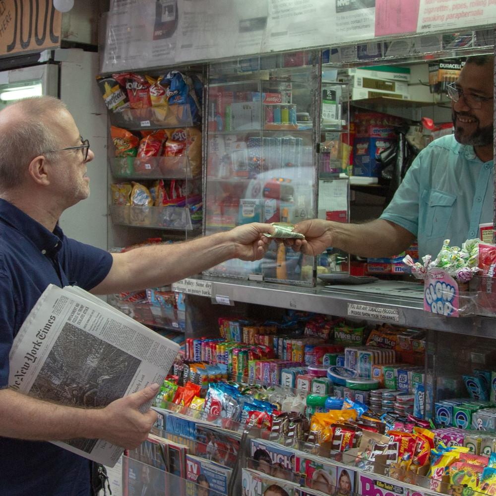 Mężczyzna kupuje gazetę w kiosku i podaje banknot przez szybkę; scena codzienności medialnej. Film dokumentalny „Letter to the Editor”, reż. Alan Berliner, MDAG 2026.